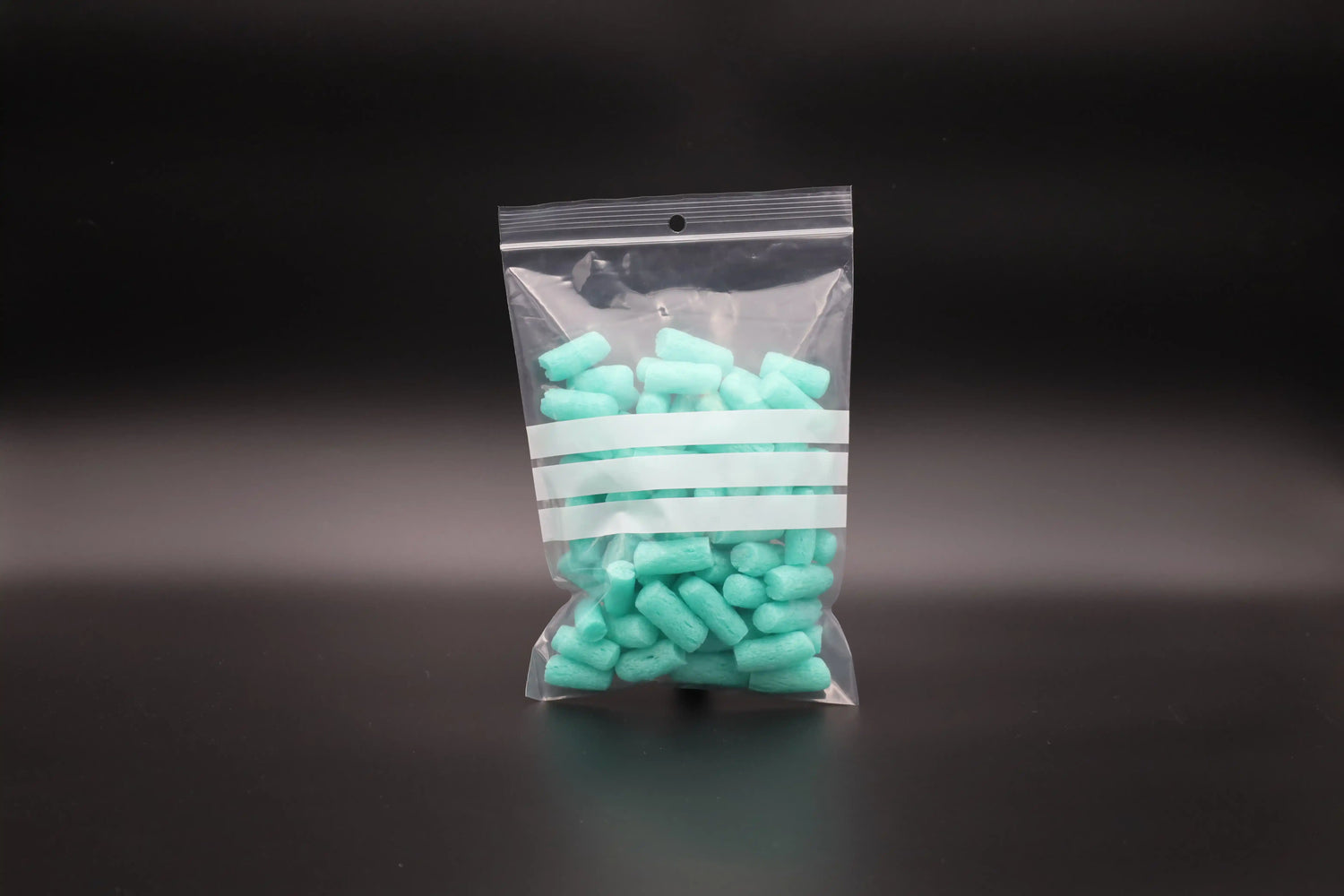 Transparenter Druckverschlussbeutel mit Beschriftungsstreifen und Rundloch, befüllt mit türkisfarbenem Füllmaterial – ideal für Lebensmittel, Kleinteile oder Versandverpackungen.