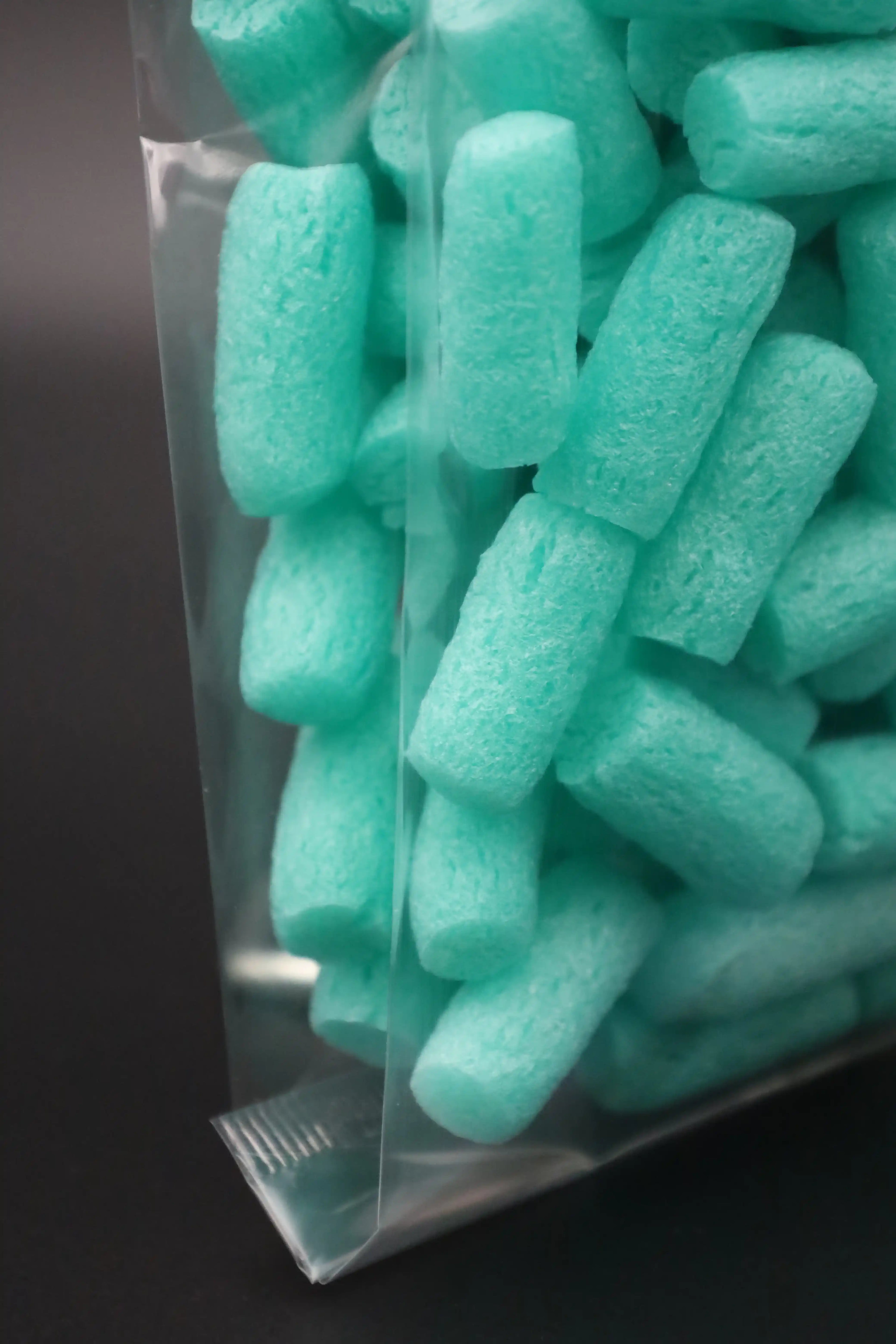 Detailaufnahme eines transparenten Kreuzbodenbeutels mit türkisfarbenen Verpackungschips