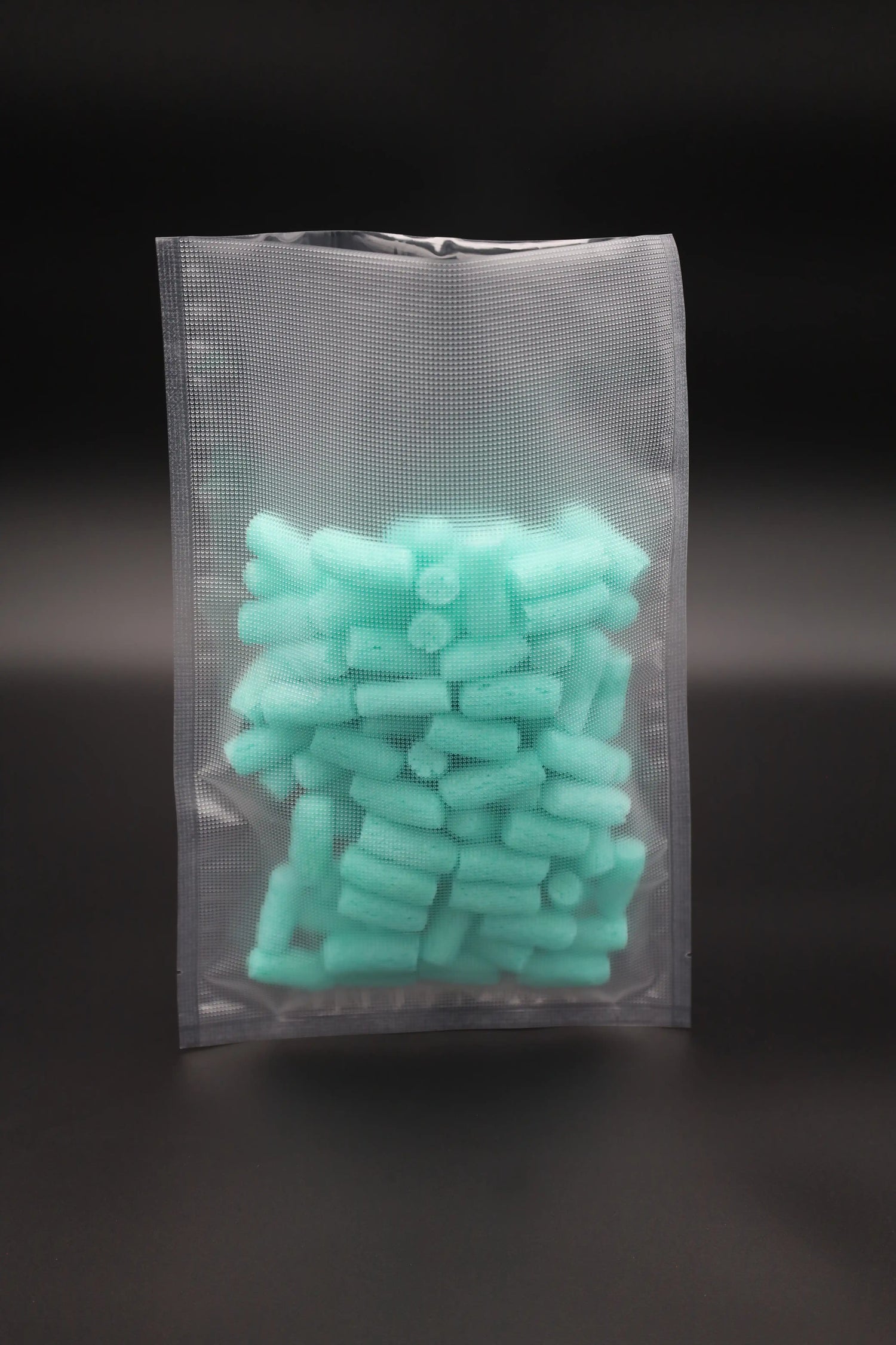 Vakuumbeutel aus strukturiertem Kunststoff, gefüllt mit türkisfarbenem Füllmaterial – ideal für luftdichte und hygienische Verpackung von Lebensmitteln oder Industrieprodukten.