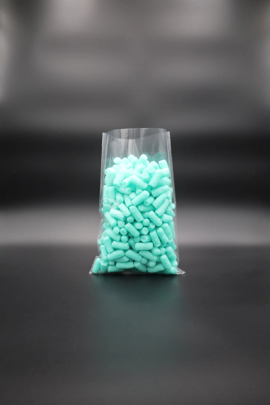 Transparenter Flachbeutel aus Kunststoff, befüllt mit türkisfarbenen Verpackungschips – ideal für leichte Produkte, platzsparend und hygienisch verpackt.